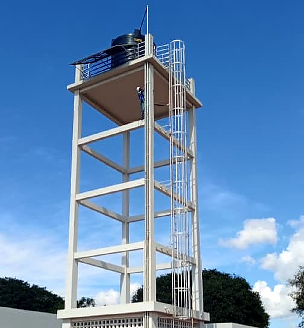 Torre de água em betão e aço com técnico a subir a escada de acesso